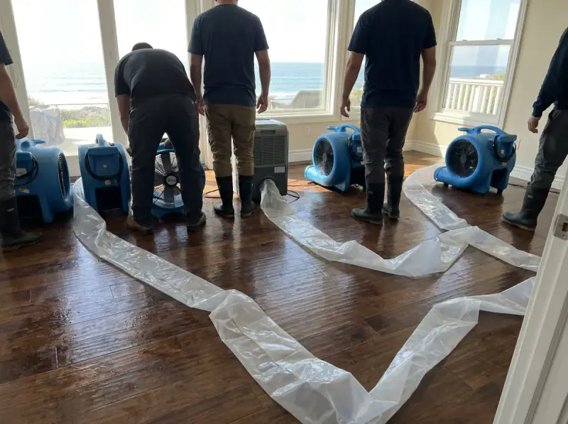 Commercial air movers and an LGR dehumidifier running on a wet floor in Huntington Beach, California