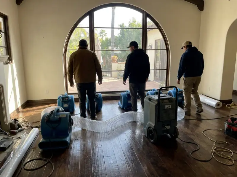 Commercial air movers and an LGR dehumidifier running on a wet floor in San Diego, California